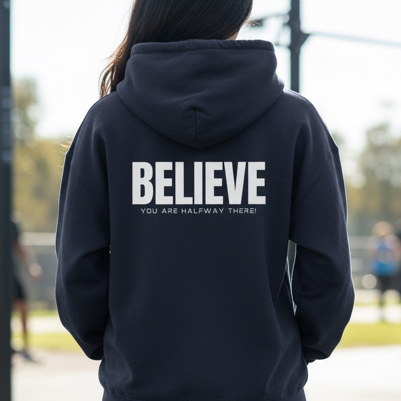 Person wearing a navy hoodie with 'BELIEVE' text on the back, standing outdoors.