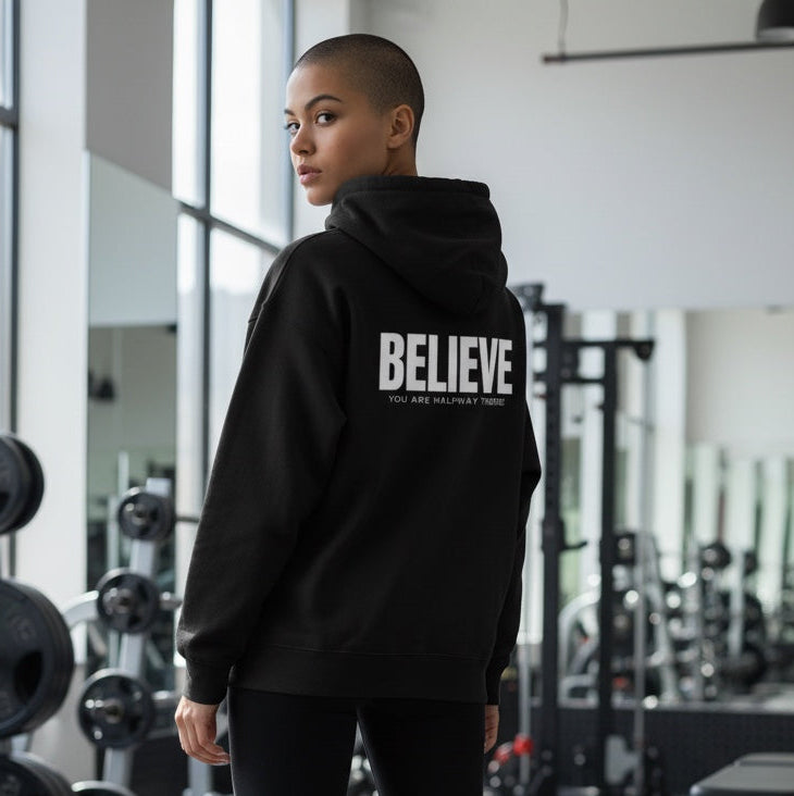 Person wearing a black hoodie with 'BELIEVE' text in a gym setting