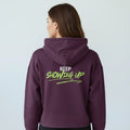 Person wearing a purple hoodie with 'KEEP SHOWING UP' text on the back against a light gray background