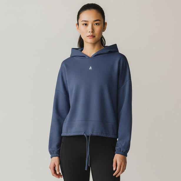 Person wearing a blue hoodie and black leggings on a plain background